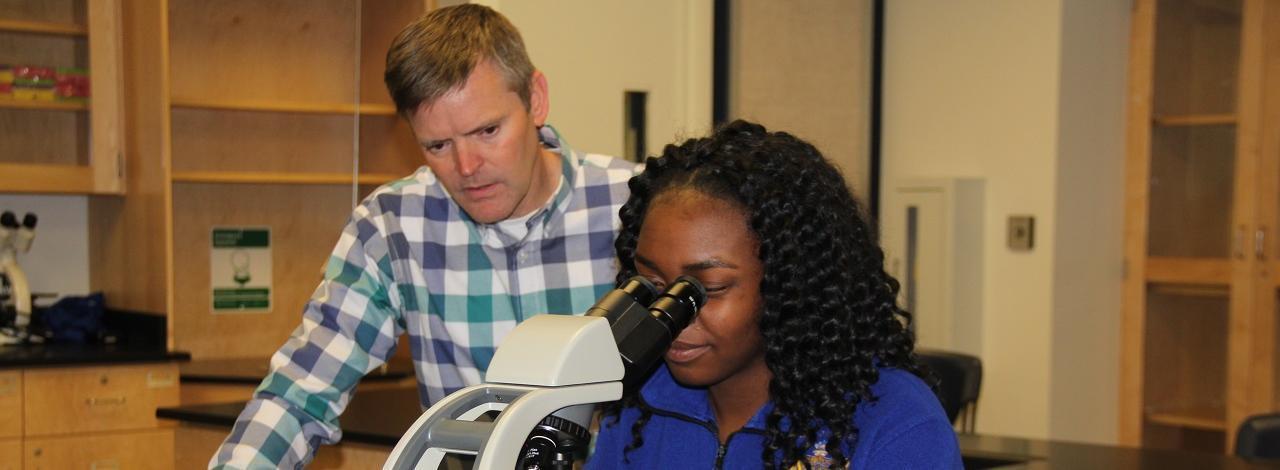 Student looking into a microscope with Bruce Fink