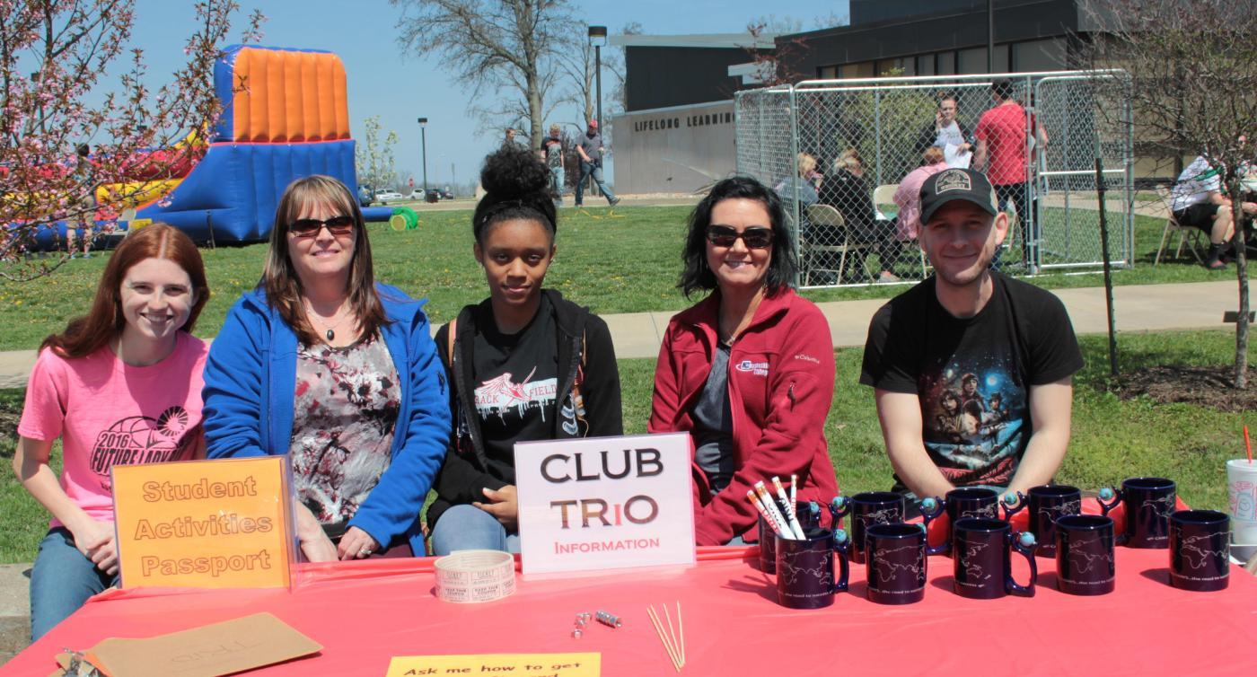 Trio Club students with table at college spring picnic