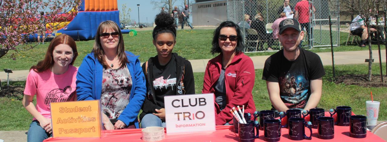 Trio Club students with table at college spring picnic